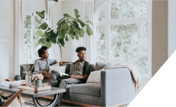 A couple sitting on a couch, gazing out of a window, enjoying a serene view together