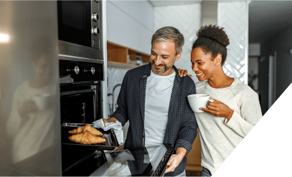 A couple joyfully retrieves freshly baked bread from the oven, showcasing their teamwork in the kitchen