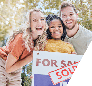 A happy family stands together, holding a sold sign, celebrating their new home with smiles and joy