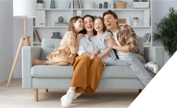 A joyful family of four sitting together on a couch, smiling and enjoying each other's company in a cozy living room