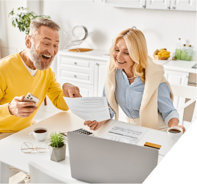 A man and woman share a joyful moment, laughing together as they review paperwork in a bright, engaging environment